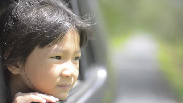 A cute girl Sit in a car and look at the scenery along the way.