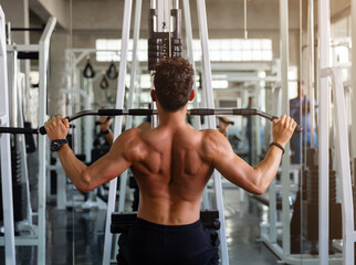 Fototapeta na wymiar Young man doing workout exercise with thrust of the upper block in the gym, Athlete training hard of bodybuilding in the gym.