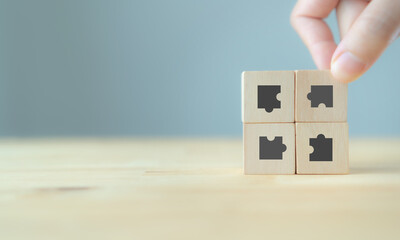 Business solutions concept. Business woman hand connecting jigsaw puzzle the icon on wooden cubes...