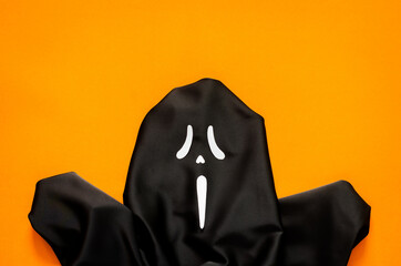 Black spooky ghost sheet with orange background for Halloween minimal background concept.
