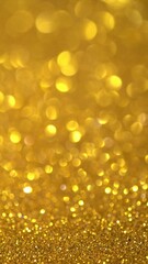 Gold Glitter Background. Magic dust, shiny texture, holiday lights, flying particles form a beautiful bokeh. Shining festive Christmas backdrop. Vertical