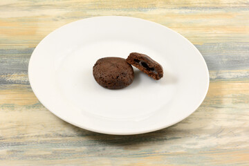 Cocoa chocolate cookies with mochi filling on white plate on table