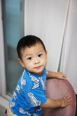Asian boy sitting on the chair looking at the camera