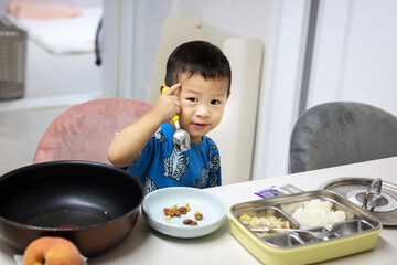 Asian boy boy holding a spoon and eating rice