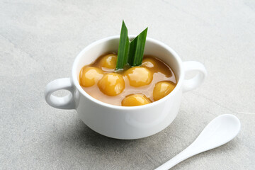 Bubur candil or kolak biji salak, Indonesian traditional food made from sticky rice flour, brown sugar and coconut milk. Popular during ramadan. Served in white bowl on grey background. Close up.
