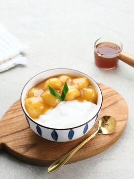 Bubur candil or kolak biji salak, Indonesian traditional food made from sticky rice flour, brown sugar and coconut milk. Popular during ramadan. Served in white bowl on grey background. Close up.
