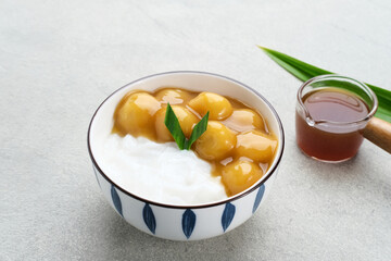 Bubur candil or kolak biji salak, Indonesian traditional food made from sticky rice flour, brown sugar and coconut milk. Popular during ramadan. Served in white bowl on grey background. Close up.
