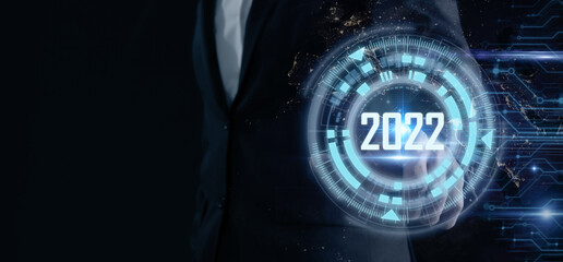 Smart businessman pointing digital dashboard in 2022 on dark blue background. Futuristic technology trend concept. Artificial intelligence (AI), machine learning support for enhancing business growth. - obrazy, fototapety, plakaty