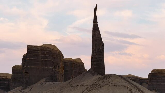 Time lapse of sunset sky over Long Dong Silver spier rock in badlands in Utah