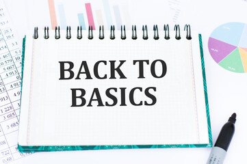 BACK TO BASICS text on an open bloncot next to a black marker on the background of financial charts