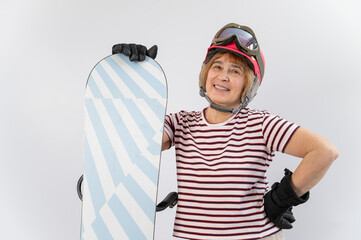 Portrait of smiling elderly woman in pink ski helmet gloves and with snowboard on white background.