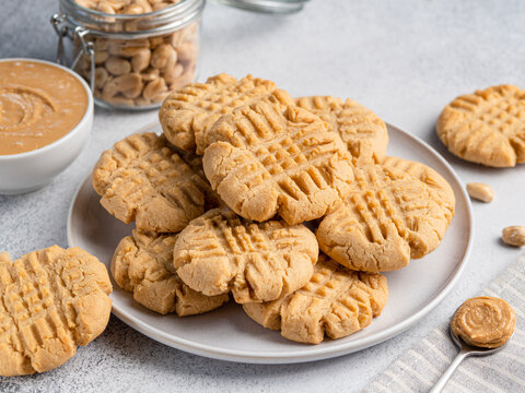 Peanut butter cookies stacked on ceramic plate. Close up view. Traditional american dessert, snack, dessert or breakfast food. Biscuits made of homemade nut butter, sugar, eggs and flour.