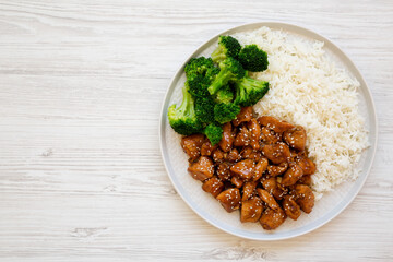 Homemade Teriyaki Chicken with Rice and Broccoli on a plate on a white wooden background, top view. Flat lay, overhead, from above. Copy space.