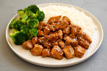 Homemade Teriyaki Chicken with Rice and Broccoli on a plate on a gray surface, side view. Close-up.