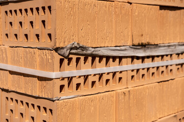 A stack of yellow and brown hollow bricks at a construction site.