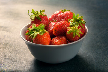 Still life with strawberries in plate on stone background