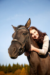 Obraz premium Woman riding a horse in filed in autumn day and blue sky background