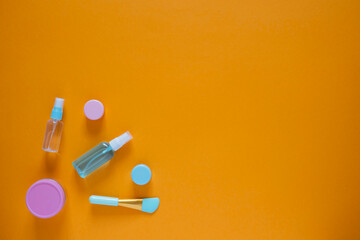Flat composition with cosmetic products on an orange background. Multicolored sponges. Women's self-care. Top view image with copy space.