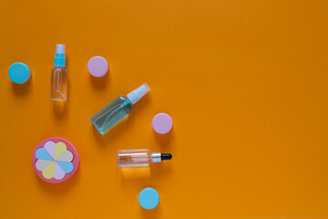 Flat composition with cosmetic products on an orange background. Multicolored sponges. Women's self-care. Top view image with copy space.