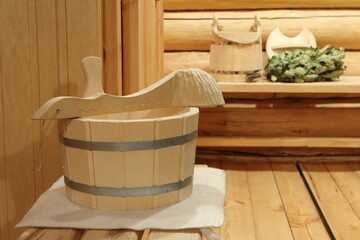 Fototapeta na wymiar Wooden buckets, ladle and oak broom are in sauna interior. 