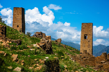 Ancient watchtowers made of brown stone against a blue sky with clouds in the mountains of...