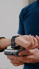Closeup of businesswoman making contactless payment with smart watch using POS terminal service. Delivery guy worker bringing takeaway food meal order during lunchtime in company office