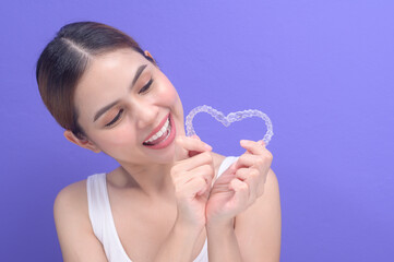 Young smiling woman holding invisalign braces in studio, dental healthcare and Orthodontic concept..