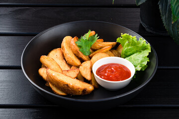 Chips Fried Potatoes. Food in a plate on a dark black table background.