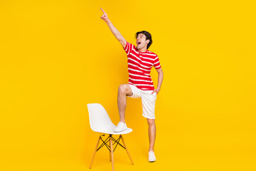 Full body photo of cheerful young happy man point finger empty space news recommend isolated on yellow color background