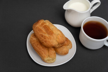 Eclairs for tea with milk. Profiteroles on white saucer. Traditional French eclairs.