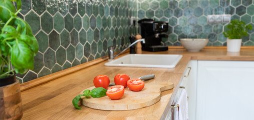 fresh tomatoes and basil in modern kitchen interior with white furniture home background