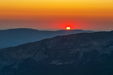 Amazing sunset over mountain range, scenic alpine landscape with dark silhouettes of mountains,...