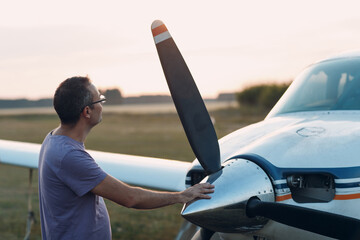 Pilot man standing next to a small private airplane