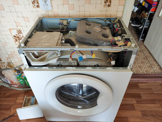 Disassembled broken washing machine in the kitchen