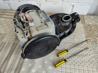 Disassembled broken vacuum cleaner and screwdrivers on the table