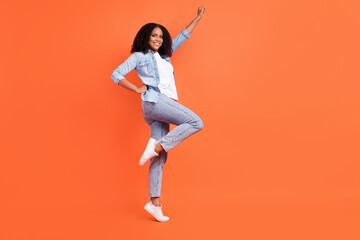 Fototapeta na wymiar Full length profile photo of cool young brunette lady wear jeans shirt shoes isolated on orange background
