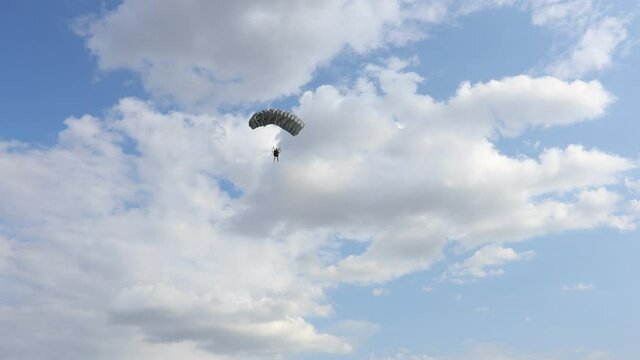 Parachute on the blue sky. Parachutist is flying slowly down with an open parachute. Skydiving, gliding, parachute jump