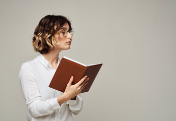 woman with curly hair in glasses with a book in her hands work by Studio
