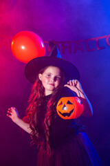Funny child girl in witch costume for Halloween with pumpkin Jack.