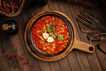 Georgian chicken chakhokhbili with tomato sauce on wooden background
