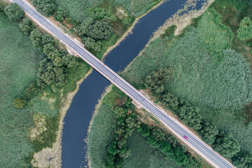 Motor road crosses the river across the bridge on a diagonal, shot from above