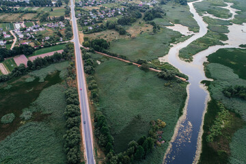 A village with an automobile asphalt road and a river passing along, shot from above