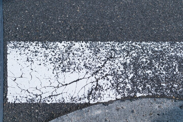 Zebra crossway with some faded on asphalt road close-up view