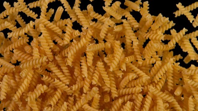 Super slow motion of flying uncooked italian pasta fusilli on black background. Filmed on high speed cinema camera, 1000 fps.