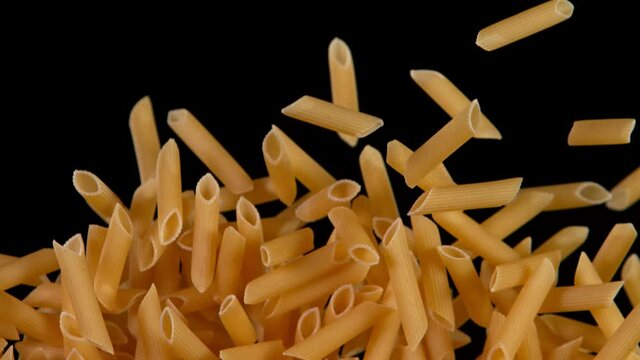 Super slow motion of flying uncooked italian pasta penne on black background. Filmed on high speed cinema camera, 1000 fps.