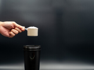 Close up of man with Whey scoop and bottle preparing protein shake.