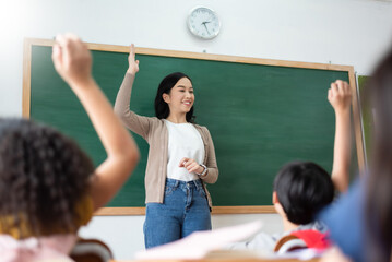 Fototapeta Asian teacher and Diverse Multi ethnic Little Student raising their hands in classroom obraz