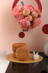 Mooncake on Light Pink Background with Pink Flower. Concept Moon Cake on Mid Autumn Festival. Mooncake Popular as Kue Bulan.