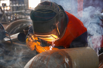 A professional welder welds a pipe with a diameter of DN250 for the process pipeline and fixes the...
