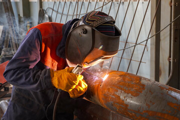 A professional welder welds a pipe with a diameter of DN250 for a process pipeline and corrects...